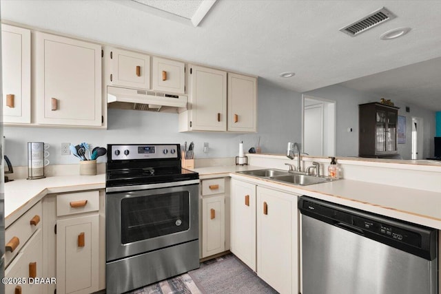 kitchen featuring a sink, appliances with stainless steel finishes, visible vents, light countertops, and under cabinet range hood