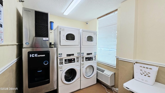 clothes washing area featuring a textured ceiling, stacked washer and dryer, an AC wall unit, and washing machine and dryer