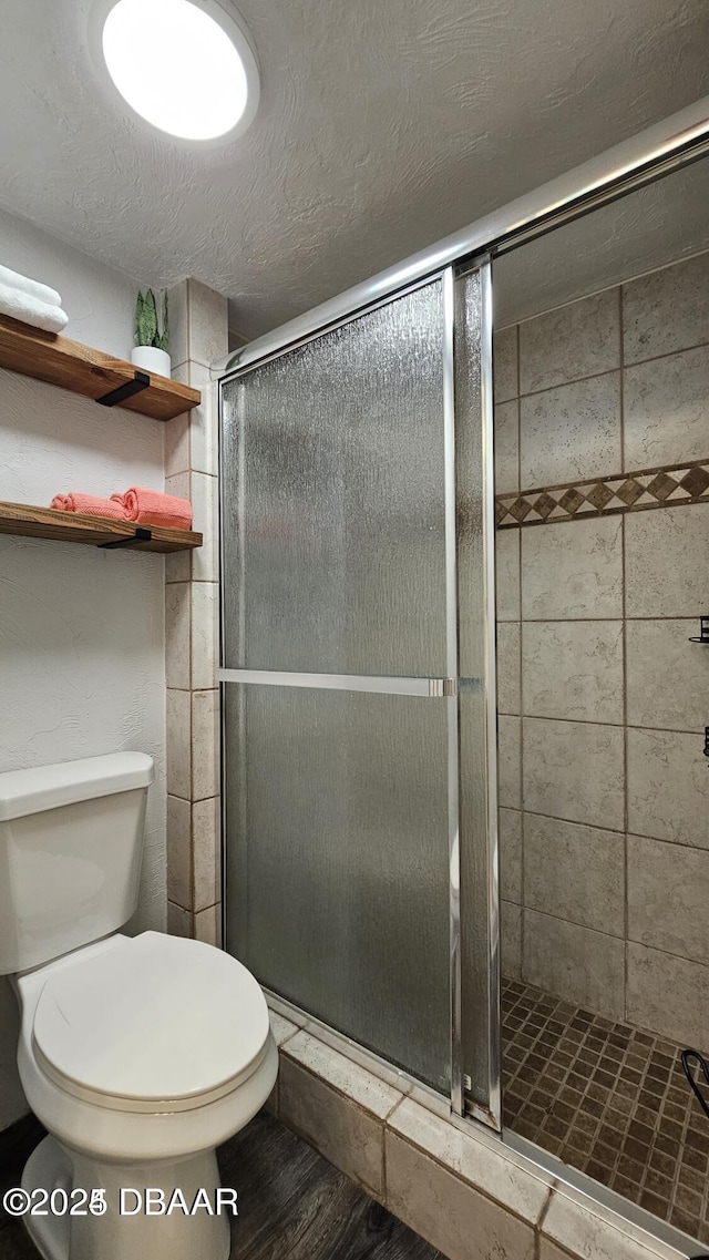 bathroom featuring toilet, wood-type flooring, a textured ceiling, and walk in shower