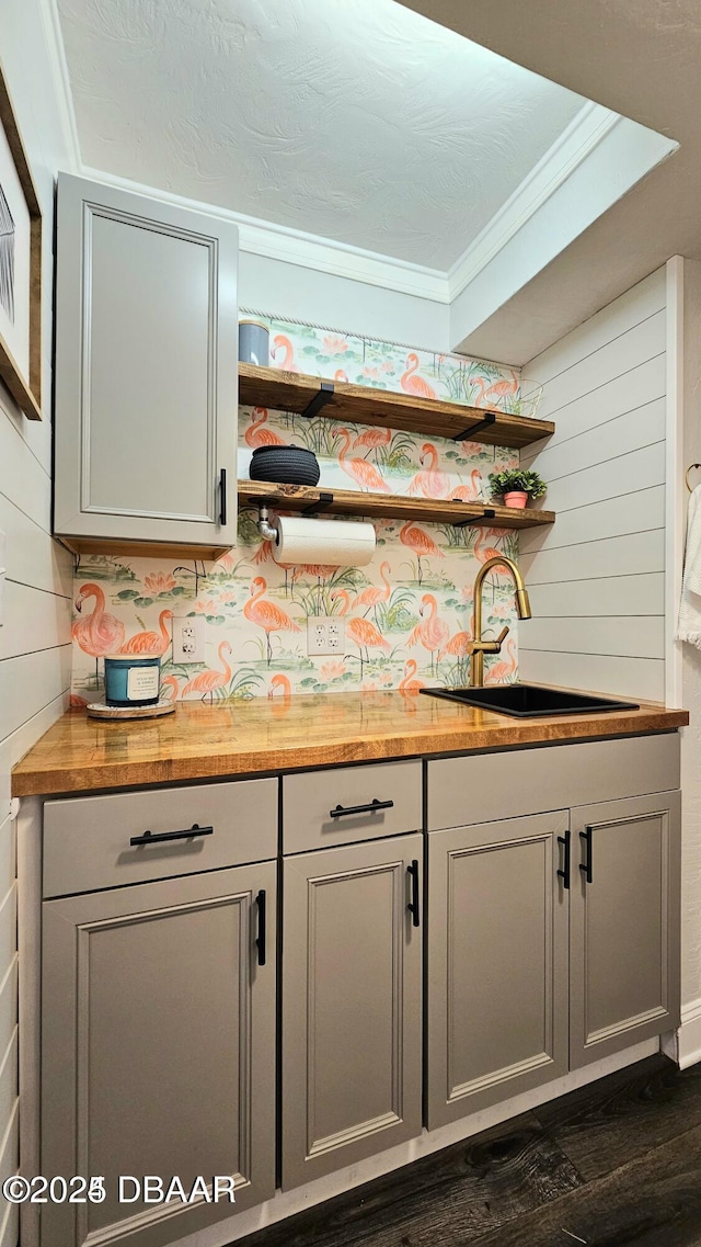 bar with gray cabinetry, sink, wooden counters, and ornamental molding