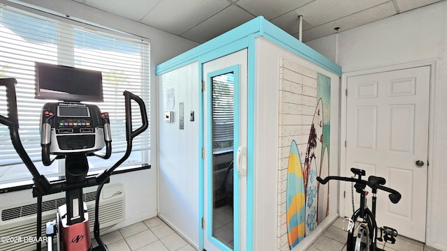 exercise room with a paneled ceiling and light tile patterned floors