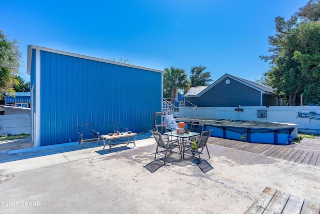 view of patio with a fenced in pool, an outdoor structure, outdoor dining space, and fence