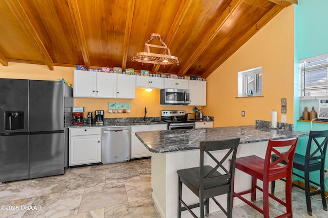 kitchen featuring dark stone countertops, stainless steel appliances, a peninsula, wooden ceiling, and white cabinets