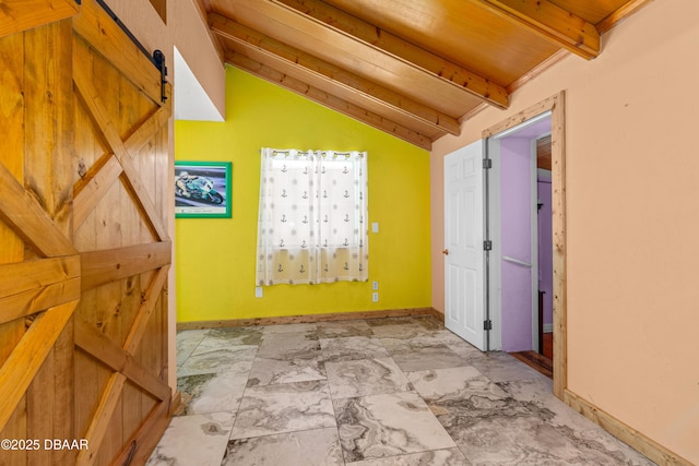 hall with lofted ceiling with beams, a barn door, and baseboards