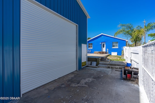 view of side of property featuring a patio, a garage, and fence