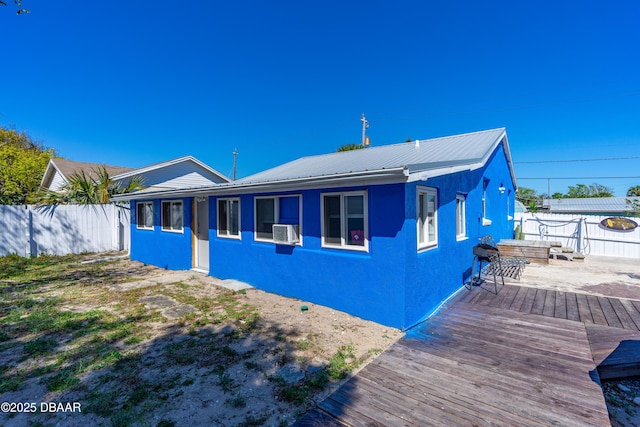 exterior space with a deck, cooling unit, fence, and metal roof