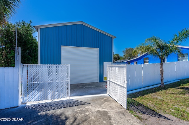 detached garage featuring driveway and fence