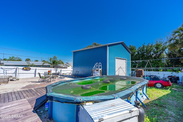 view of outdoor structure with an outbuilding, a fenced backyard, and outdoor dining space