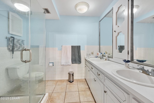 49 Bosarvey Cir, Ormond Beach, FL 32176 - bathroom featuring tile walls, double vanity, tile patterned floors, a stall shower, and a wainscoted wall