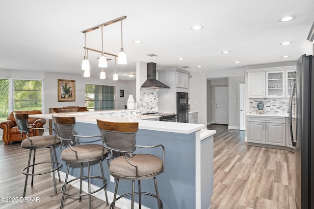 49 Bosarvey Cir, Ormond Beach, FL 32176 - kitchen featuring wall chimney range hood, freestanding refrigerator, decorative backsplash, a kitchen bar, and recessed lighting