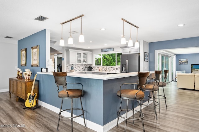 49 Bosarvey Cir, Ormond Beach, FL 32176 - kitchen with stainless steel fridge, a breakfast bar area, white cabinetry, light wood-style floors, and recessed lighting