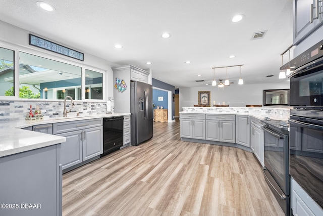 49 Bosarvey Cir, Ormond Beach, FL 32176 - kitchen featuring black appliances, gray cabinetry, light wood finished floors, tasteful backsplash, and light countertops