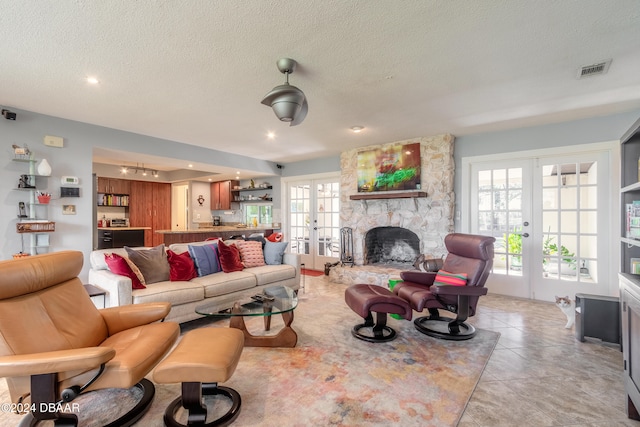 tiled living room with a fireplace, a wealth of natural light, french doors, and a textured ceiling