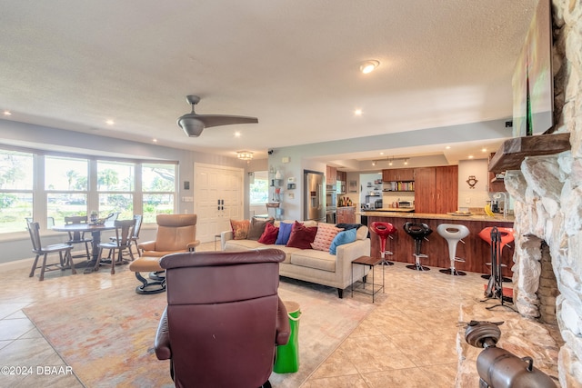 tiled living room with ceiling fan and a textured ceiling