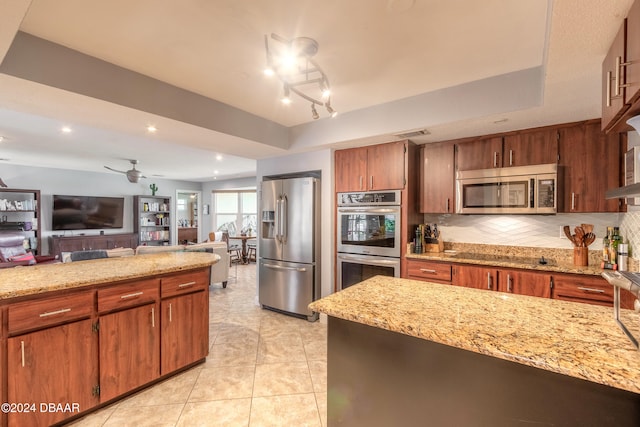 kitchen featuring ceiling fan with notable chandelier, light tile patterned floors, tasteful backsplash, light stone countertops, and appliances with stainless steel finishes