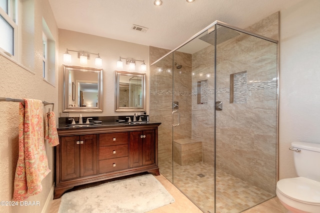 bathroom with tile patterned floors, toilet, a textured ceiling, an enclosed shower, and vanity