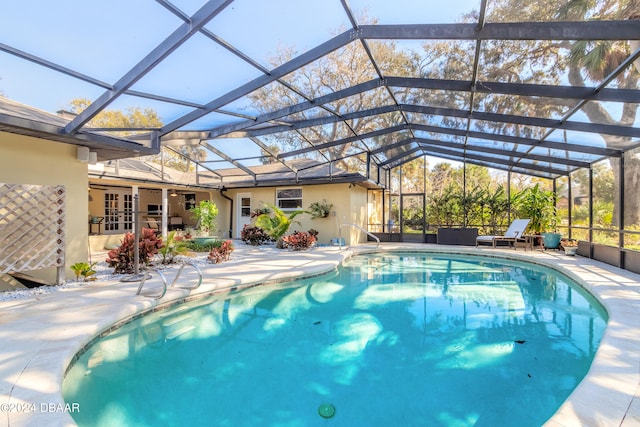 view of pool with glass enclosure and a patio area