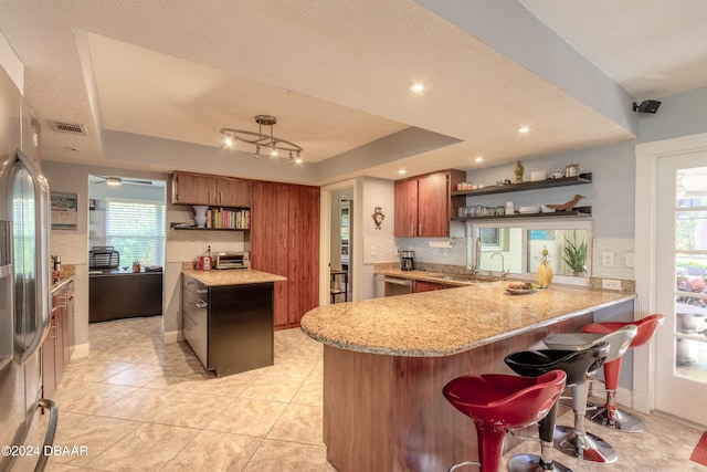 kitchen featuring a tray ceiling, kitchen peninsula, and plenty of natural light