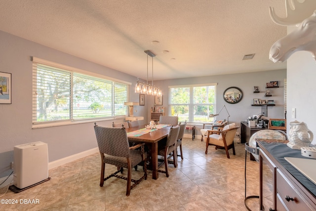 tiled dining space featuring a healthy amount of sunlight and a textured ceiling