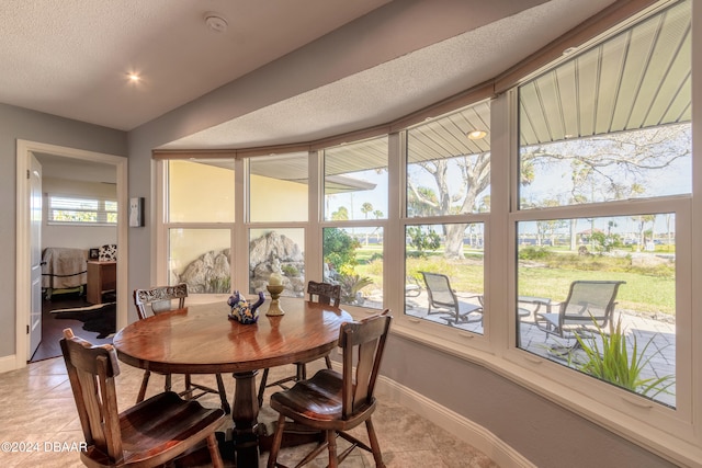 tiled dining room with a textured ceiling and a healthy amount of sunlight