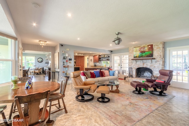 tiled living room featuring a fireplace, a wealth of natural light, a textured ceiling, and french doors