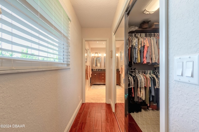 corridor with hardwood / wood-style floors and a textured ceiling