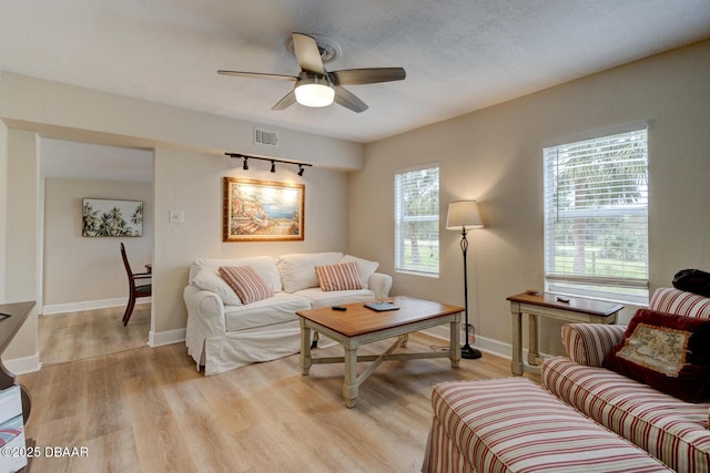 living room featuring a textured ceiling, light hardwood / wood-style floors, and ceiling fan