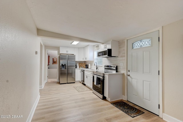 kitchen with white cabinetry, sink, stainless steel appliances, and light wood-type flooring