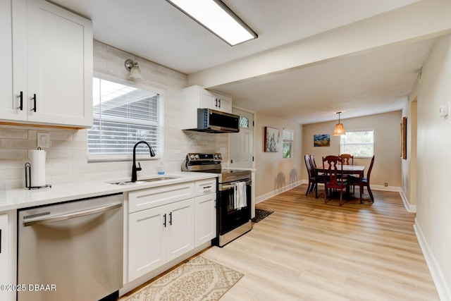 kitchen with tasteful backsplash, white cabinetry, sink, stainless steel appliances, and light hardwood / wood-style flooring