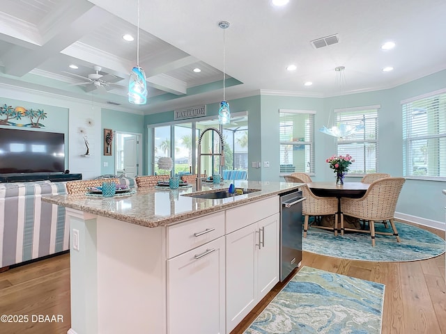 kitchen featuring beam ceiling, sink, an island with sink, and coffered ceiling