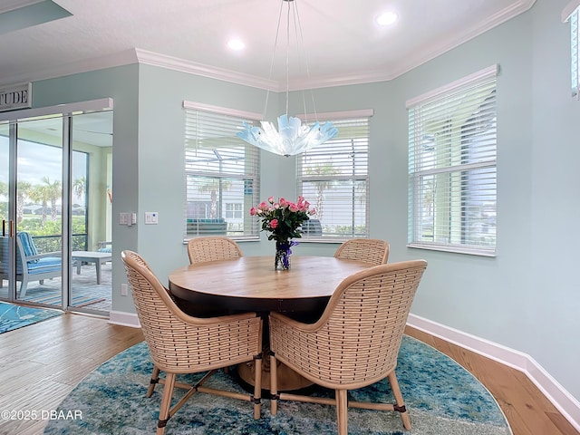 dining area featuring hardwood / wood-style floors, ornamental molding, and a notable chandelier