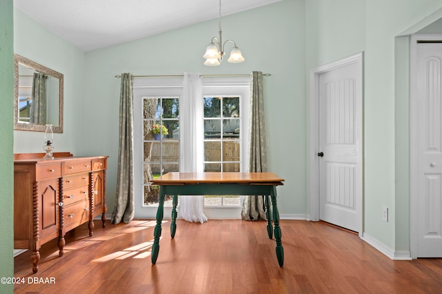 dining area with wood-type flooring, lofted ceiling, and a notable chandelier