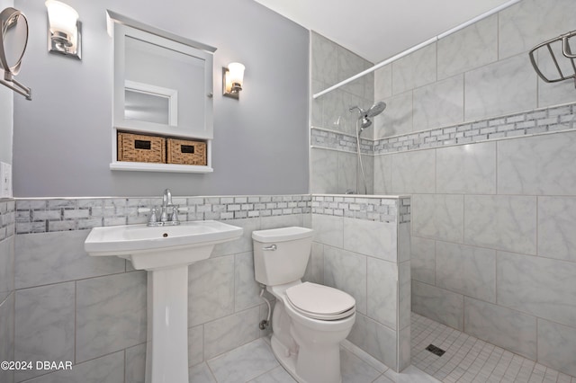 bathroom featuring toilet, tile walls, tile patterned floors, and a tile shower