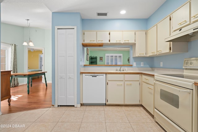 kitchen with cream cabinetry, white appliances, decorative light fixtures, and light tile patterned flooring