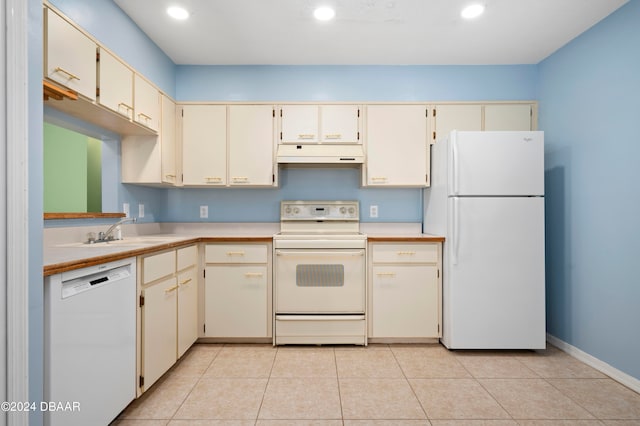 kitchen featuring cream cabinetry, sink, white appliances, and light tile patterned floors