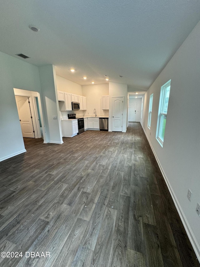 8 Phoenix Ln, Palm Coast, FL 32164 - unfurnished living room featuring dark wood-type flooring, baseboards, and recessed lighting