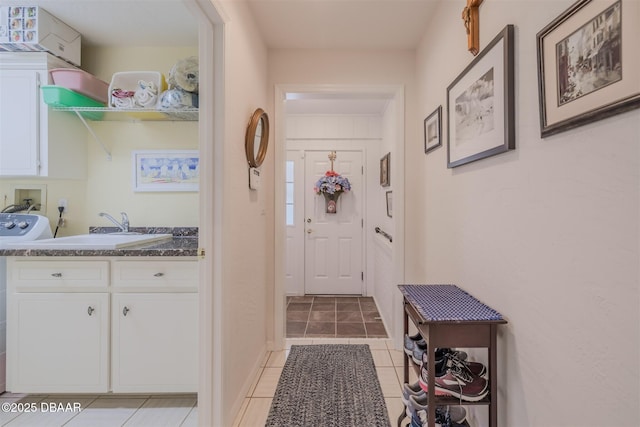 doorway with washer / clothes dryer, sink, and light tile patterned floors