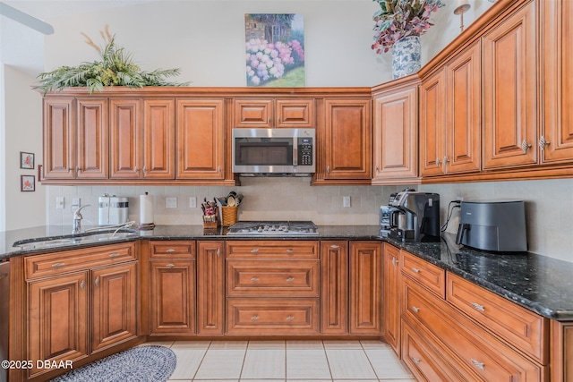 kitchen with sink, decorative backsplash, dark stone counters, and appliances with stainless steel finishes