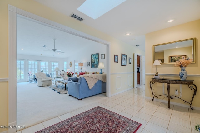 tiled living room with a skylight and ceiling fan