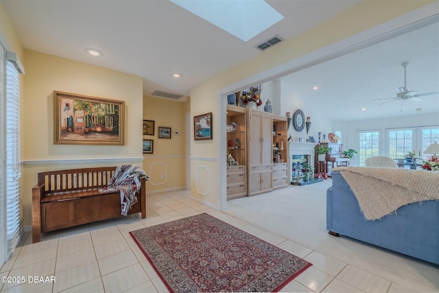 living room with ceiling fan, a skylight, and light tile patterned floors