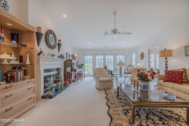 living room featuring ceiling fan, light colored carpet, a fireplace, and vaulted ceiling