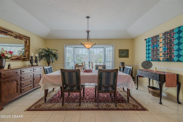 tiled dining space featuring lofted ceiling and a raised ceiling