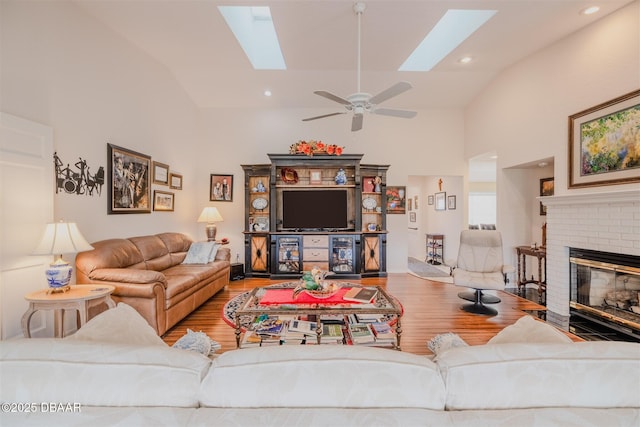 living room featuring light hardwood / wood-style floors, high vaulted ceiling, a fireplace, and a skylight