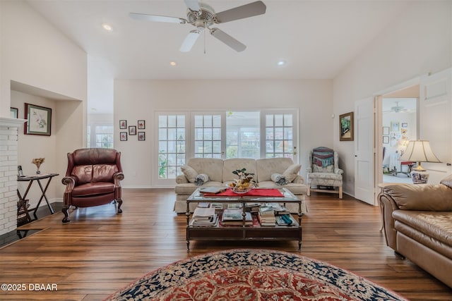 living room with dark wood-type flooring, ceiling fan, and a brick fireplace