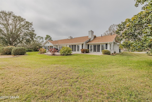 rear view of property with french doors and a lawn