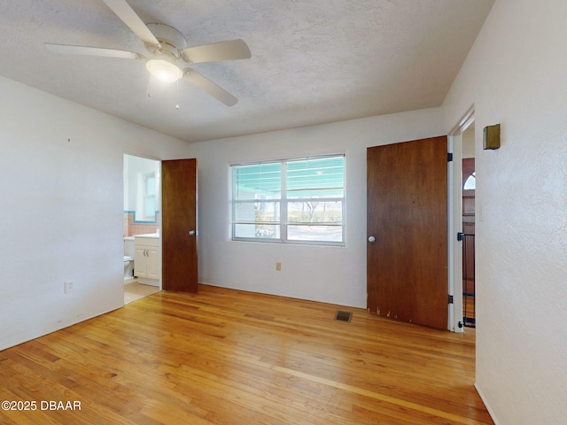 empty room featuring ceiling fan, a textured ceiling, and light hardwood / wood-style flooring