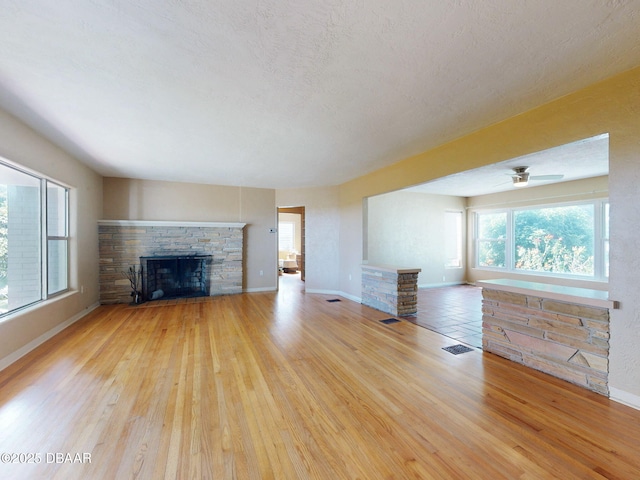 unfurnished living room with a fireplace, light hardwood / wood-style flooring, and a textured ceiling