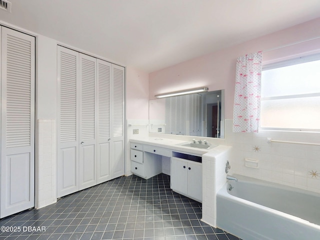 bathroom featuring vanity, tile patterned flooring, and a washtub