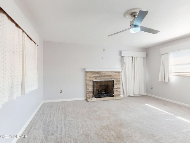 unfurnished living room featuring a stone fireplace, light colored carpet, and ceiling fan