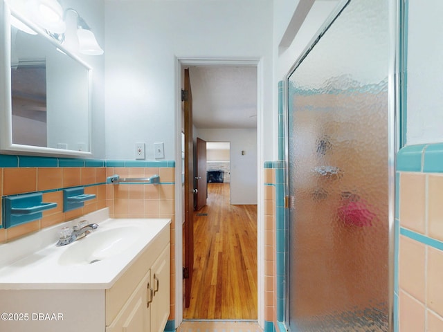 bathroom featuring an enclosed shower, vanity, and tile walls